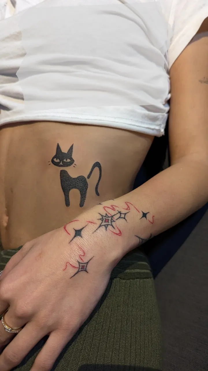 Black cat on the ribs, with sparkles on the hand