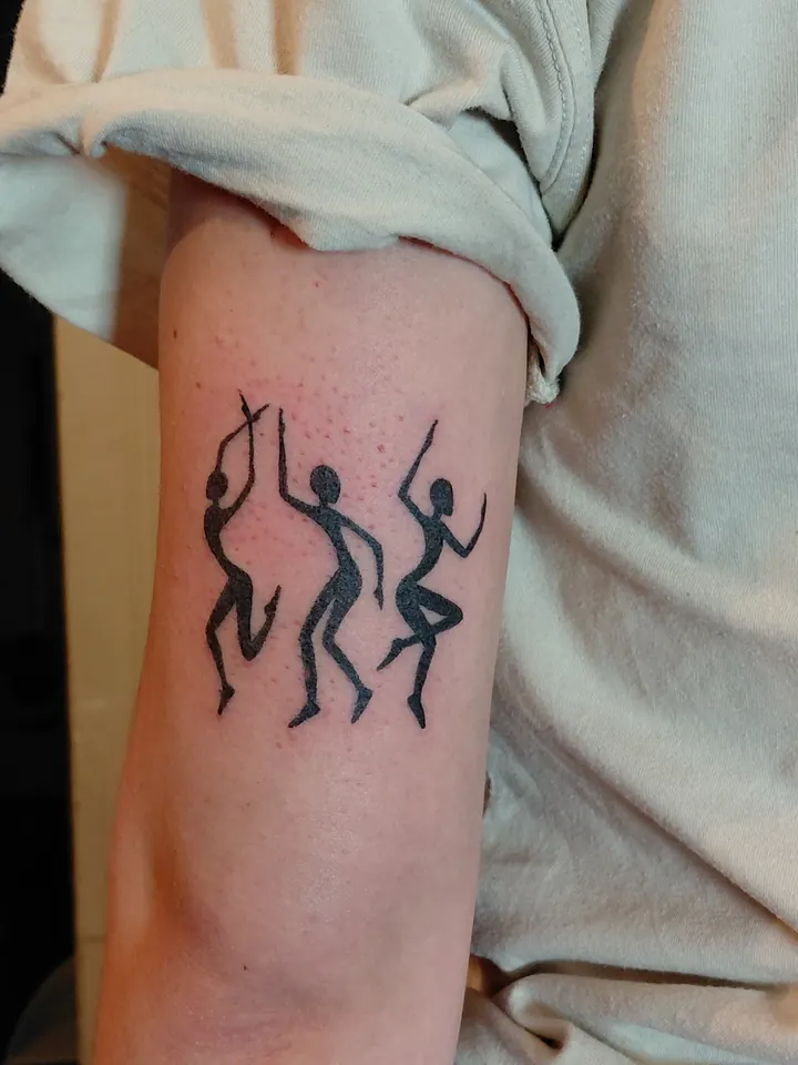 Three dancing figures in solid black on the upper arm
