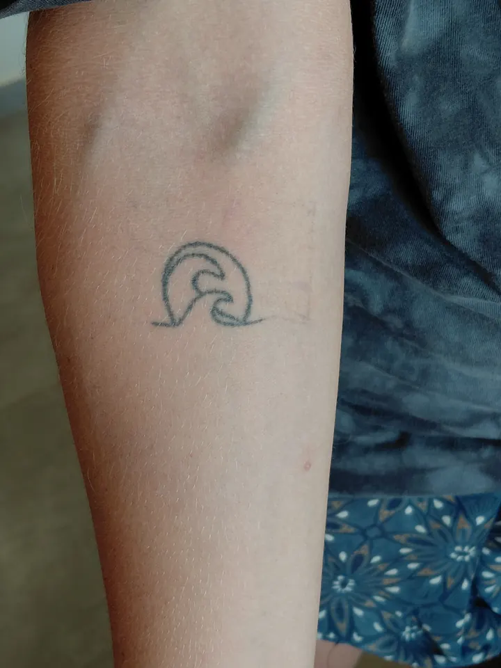 Cover-up, before: a small wave tattoo on the forearm