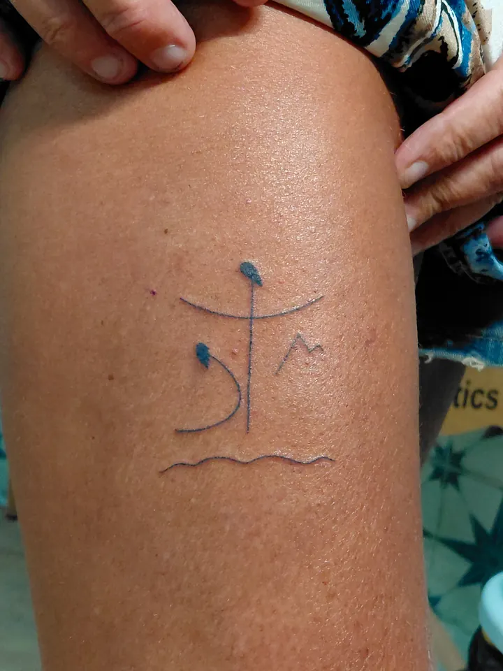 Small blue-ink symbol with a mountain and a wavy sea line
