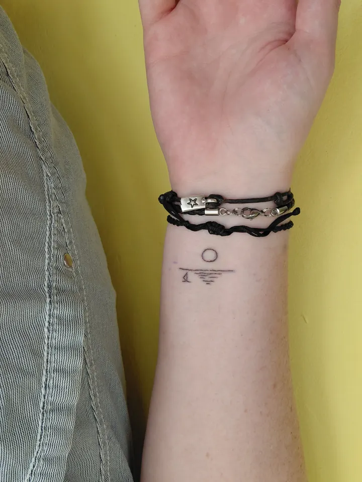 Tiny sun setting over the sea on the wrist